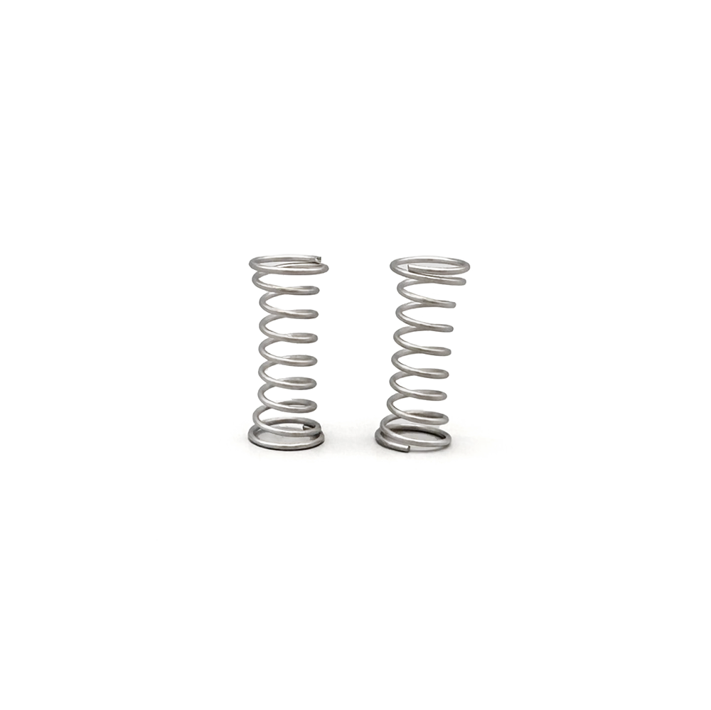 Two small silver metal coil springs standing upright on a plain white background.